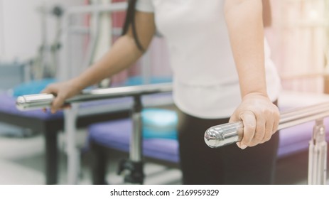 Close up older woman patient walking on parallel bars in rehab room on the background in hospital, health problem and medical concept. - Powered by Shutterstock