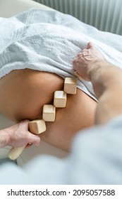 Close up on back of unknown woman having madero therapy massage anti-cellulite treatment by professional therapist holding wooden tools in hands in studio or salon with copy space