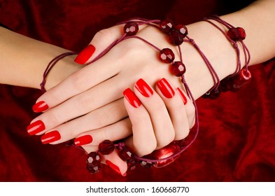 Close up on beautiful female hands with sexy red manicure. Red velvet background. - Shutterstock ID 160668770