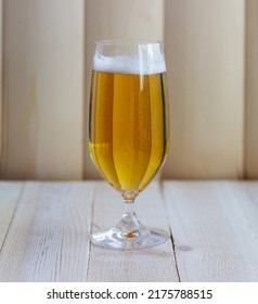 Close Up On A Beer Glass Filled With A Pale Blonde Ale, On A Wood Table At The Bar