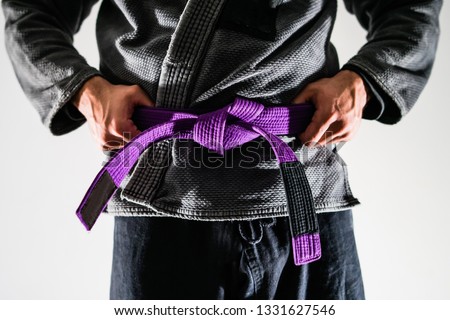 Close Up On Brazilian Jiu JItsu BJJ Fighter in a Gi Kimono Holding Purple Belt around his waist