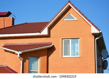 Close Up On Brick House With Asphalt Shingles Roof And Rain Gutters In Problem Area.