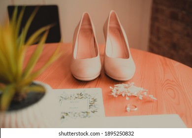 Close Up On Bride Wedding Shoes, Diamond Ring, And Ceremony Hair Piece On Interior Table With Succulent Plant And Wood Texture