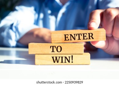 Close up on businessman holding a wooden block with "Enter to Win" message - Shutterstock ID 2250939829