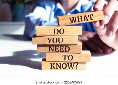 Close up on businessman holding a wooden block with "What Do You Need to Know?" message