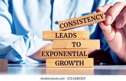 Close up on businessman holding a wooden block with a "Consistency leads to exponential growth" message - Shutterstock ID 2311680329