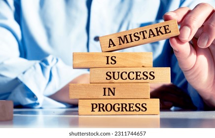 Close up on businessman holding a wooden block with a "A Mistake is a Success in Progress" message - Shutterstock ID 2311744657