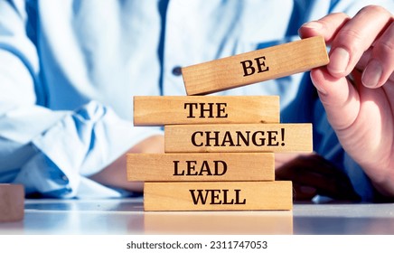 Close up on businessman holding a wooden block with a "Be the change, lead well" message - Shutterstock ID 2311747053