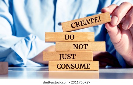 Close up on businessman holding a wooden block with a "Create, do not just consume" message - Shutterstock ID 2311750729