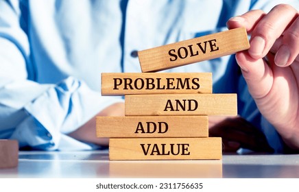Close up on businessman holding a wooden block with a "Solve problems and add value" message - Shutterstock ID 2311756635