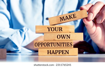 Close up on businessman holding a wooden block with a "Make your own opportunities happen" message - Shutterstock ID 2311765241