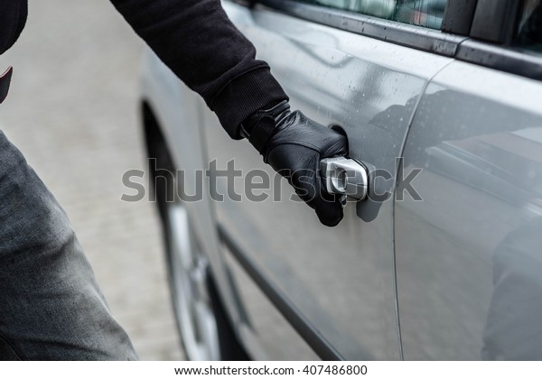 Close up on car thief hand pulling the
handle of a car. Car thief, car theft
concept