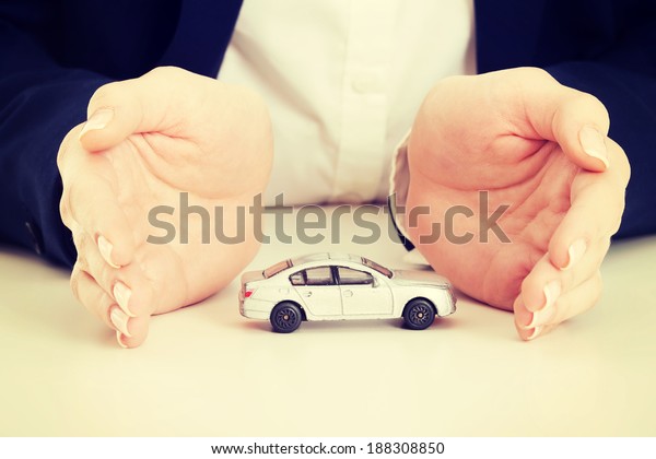 Close up on car toy model between hands lying on\
the table.