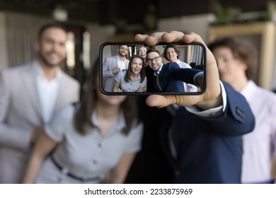 Close up on cellphone screen view of group of happy business people holding smartphone looking at device screen make selfie picture having fun during break at workplace. Friendship, modern tech, apps - Powered by Shutterstock