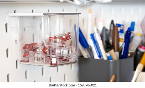 Close Up On Clips Stored Inside A Clear Box Hanging From Peg Board As A Storage Idea For Craft Room Or Workshop Wall