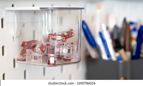 Close Up On Clips Stored Inside A Clear Box Hanging From Peg Board As A Storage Idea For Craft Room Or Workshop Wall