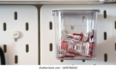 Close Up On Clips Stored Inside A Clear Box Hanging From Peg Board As A Storage Idea For Craft Room Or Workshop Wall