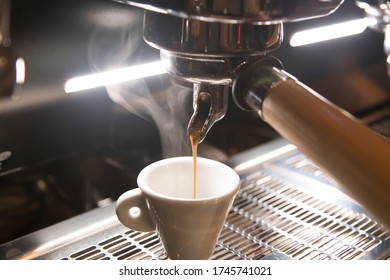 Close Up On A Coffee Cup Filled By The Coffee Machine Of A Bar. No People Are Visible. Low Key Image.