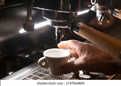 Close Up On A Coffee Cup Filled By The Coffee Machine Of A Bar. No People Are Visible. Low Key Image.