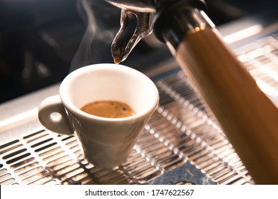 Close Up On A Coffee Cup Filled By The Coffee Machine Of A Bar. No People Are Visible. Low Key Image.