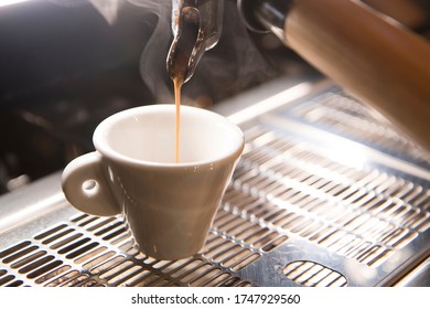 Close Up On A Coffee Cup Filled By The Coffee Machine Of A Bar. No People Are Visible. Low Key Image.