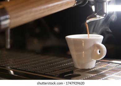 Close Up On A Coffee Cup Filled By The Coffee Machine Of A Bar. No People Are Visible. Low Key Image.