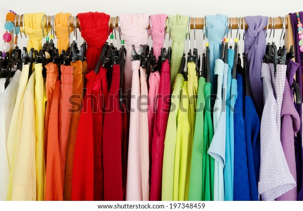 Close up on color coordinated clothes on\
hangers in a store. Detail on all colors clothes hanging on a rack\
nicely arranged.