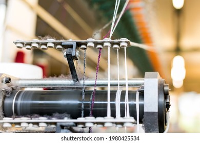 Close Up On Colored Cashmere Wool Yarn Threaded Through A Feeder On Top Of A Commercial Knitting Machine In A Knitwear Factory