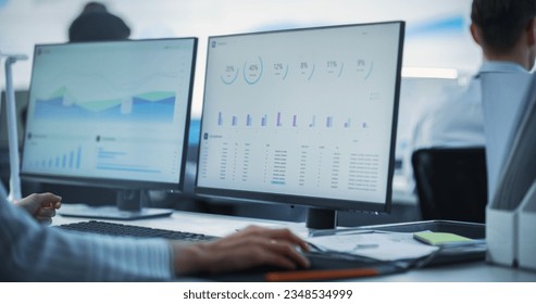 Close Up on Computer Monitors of Male Financial Data Analyst Using Laptop And Studying Information And Graphs On Big Digital Screen In Monitoring Office. Man Working For Big Consulting Firm