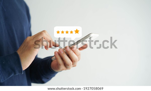 close up on customer man hand pressing on\
smartphone screen with gold five star rating feedback icon and\
press level excellent rank for giving best score point to review\
the service , business\
concept