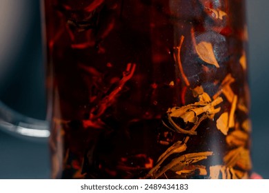 close up on dark blue background with side lighting stands a glass modern teapot with a press for brewing black tea floating tea leaves - Powered by Shutterstock