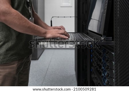 Close up on Data Center Engineer hands Using keyboard on a supercomputer Server Room Specialist Facility with Male System Administrator Working with Data Protection Network for Cyber Security.