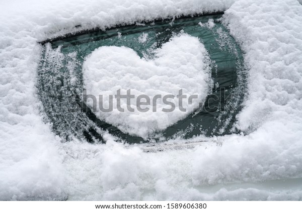 close up on drawing hearts on car windshield after snow 
       