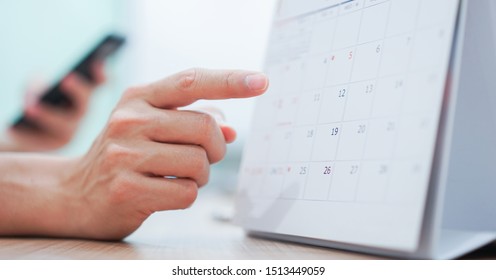 close up on employee man hand using finger pointing schedule (timetable) on calendar to make appointment meeting or manage timetable each day , life balance concept - Shutterstock ID 1513449059