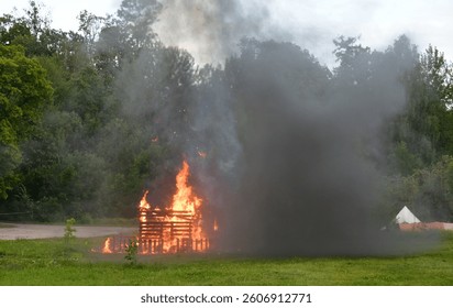 A close up on an exploded hut, shack or shelter and flaming wooden elements seen during a military reenactment involving explosives, antique carts and soldiers organized in summer in Poland