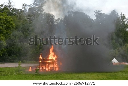A close up on an exploded hut, shack or shelter and flaming wooden elements seen during a military reenactment involving explosives, antique carts and soldiers organized in summer in Poland