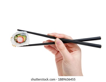 Close up on female caucasian hand holding black chop sticks with one California roll sushi, isolated on white.
