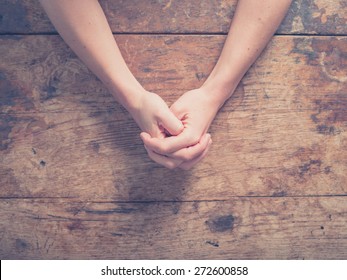 Close up on female hands folded in prayer at a wooden table