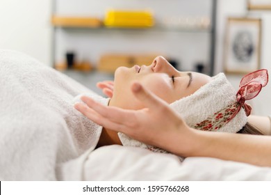 Close up on female woman hands on the face of the young girl giving her relax massage at spa studio relaxing unknown masseur therapist facial therapy treatment caucasian client covered with white