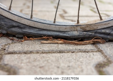 Close Up On The Flat Deflated Tyre If A Bicycle With Puncture Iutdoors On Paving