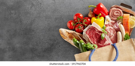 Close up on fresh groceries in a shopping bag over a textured slate background fresh groceries including assorted meat, fish, baguette, tomatoes, sweet peppers and herbs - Powered by Shutterstock