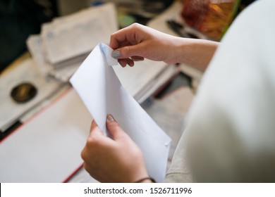 Close Up On Girl Female Woman Hands Holding And Opening White Envelope By The Table At Office Work Or At Home With Bills Mail Or Insurance Contract Invoice Letter