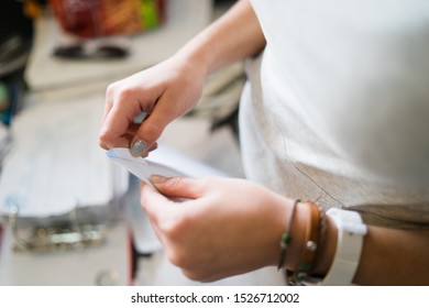 Close up on girl female woman hands holding and opening white envelope by the table at office work or at home with bills mail or insurance contract invoice letter