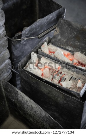 Close up on glowing charcoal coals in old metal baskets, at a traditional Korean barbecue restaurant, with space for text on top and bottom
