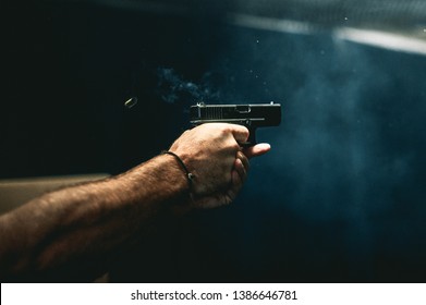 close up on a guy shooting firearm handgun, glock pistol in a firing range 
