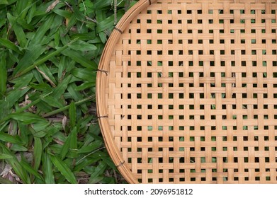 Close Up On Half Bamboo Wicker Basket On Green Grasses Background From Top View. Empty Native Thai Wooden Basket With Copy Space With Overhead View. Natural Wicker Basket On Green Grass.