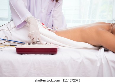 Close up on hand doctor seting electriccal atimulator with woman undergoing acupuncture treatment with electrical stimulator 