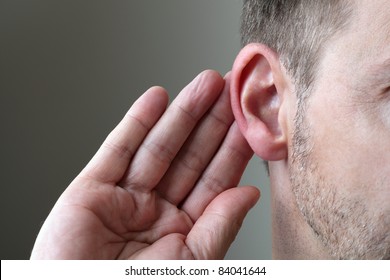 Close up on hand and ear listening for a quiet sound or paying attention