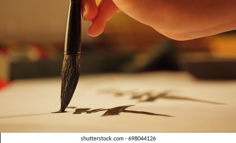 Close up on hand holding brush while writing calligraphy