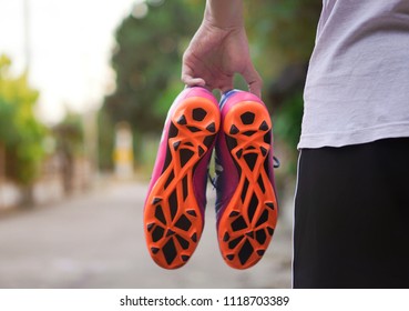 Close Up On The Hand Is Holding The Football Boots Or Soccer Boots With Blur Background.